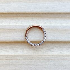 Clicker de titanio con baño de oro rosa y zirconias frontales