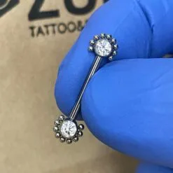 Piercing de pezón. De titanio con filigranas y con zirconias blancas y rosca interna.
