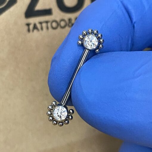 Piercing de pezón. De titanio con filigranas y con zirconias blancas y rosca interna.