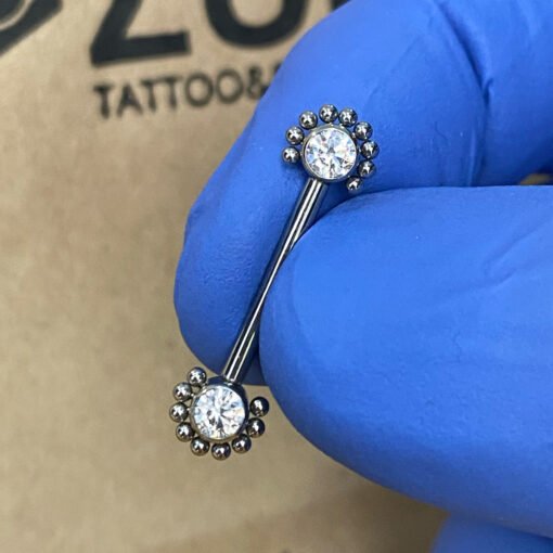 Piercing de pezón. De titanio con filigranas y con zirconias blancas y rosca interna.